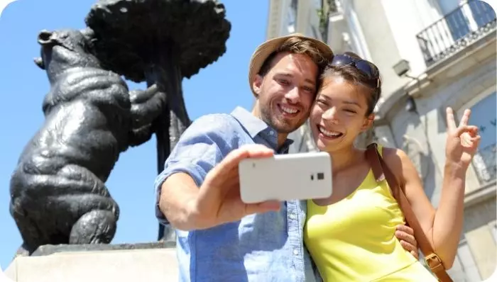 Couple taking a selfie with the sculpture of "El Oso y el Madroño" in Madrid
